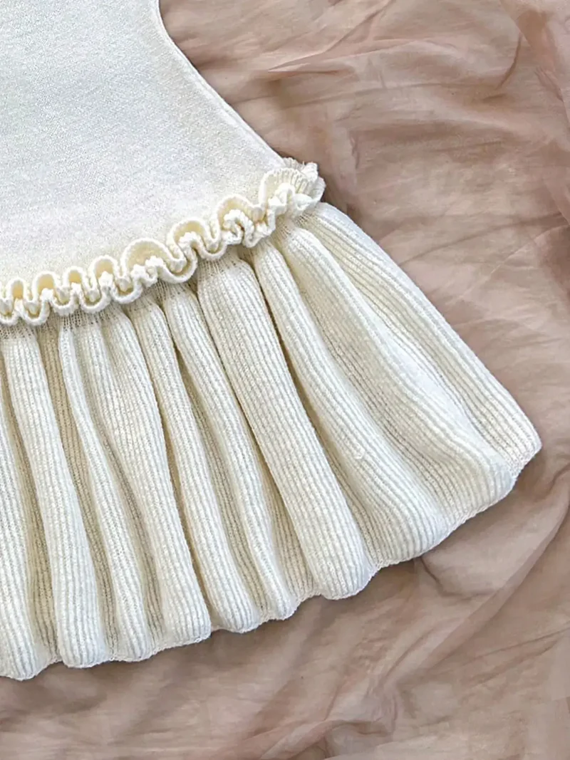 Damesjurk met halternek, ruches aan de zoom, strikdetail en lichte stretch.