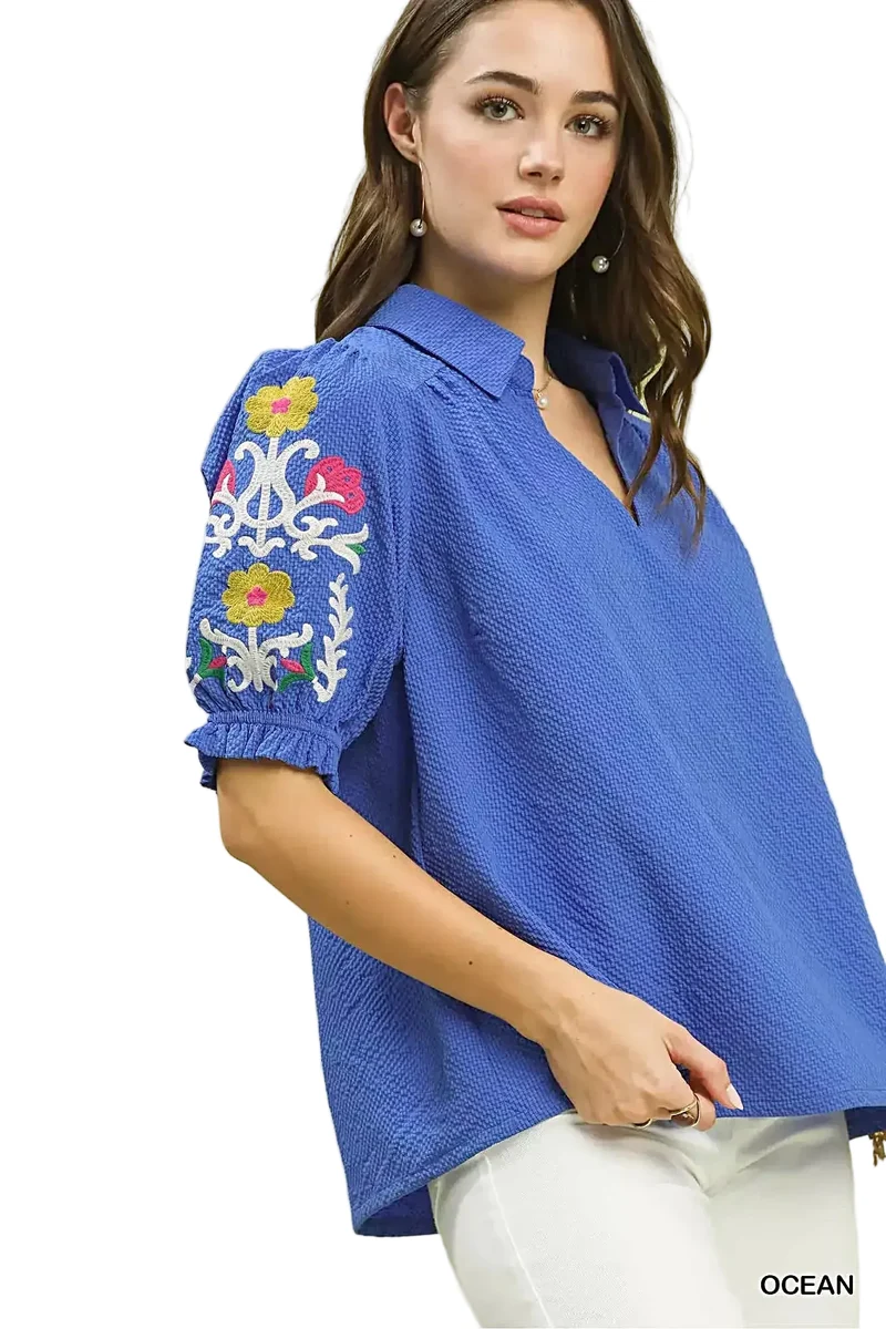 Elegante top van 100% polyester seersucker met geborduurde mouwen en een verfijnde open kraag.