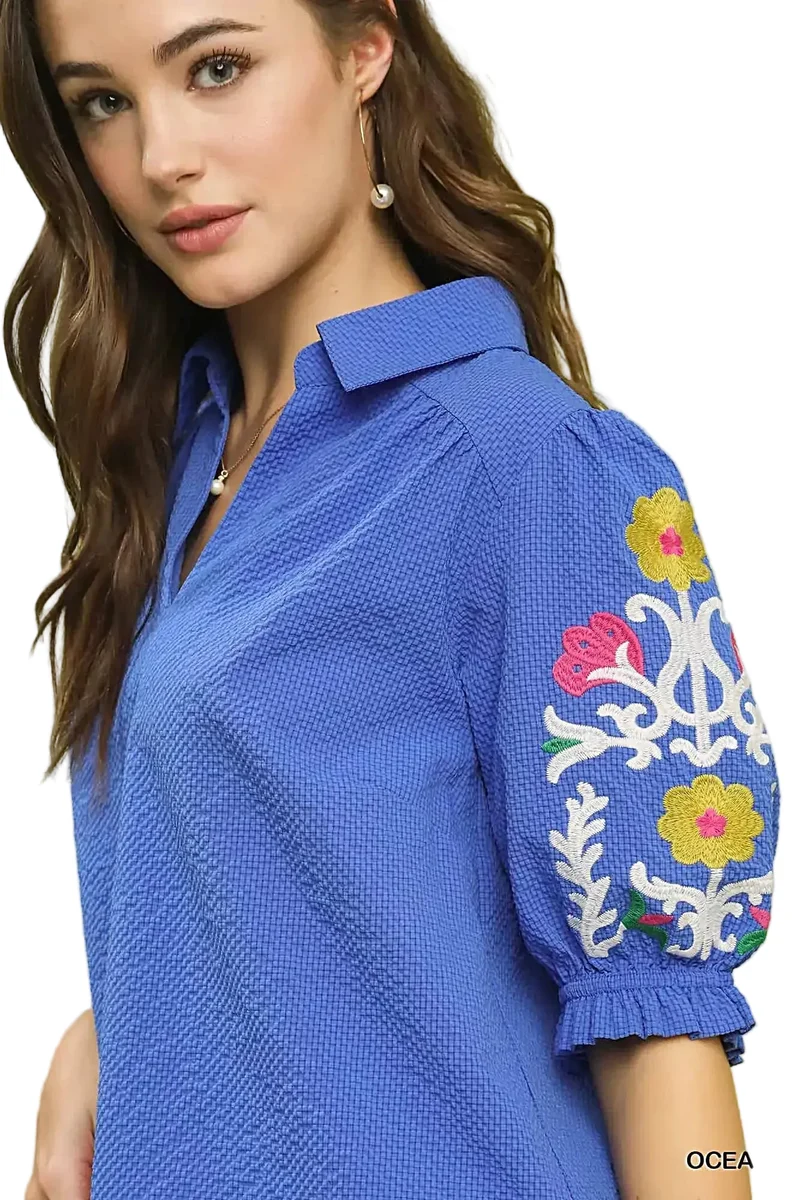 Elegante top van 100% polyester seersucker met geborduurde mouwen en een verfijnde open kraag.