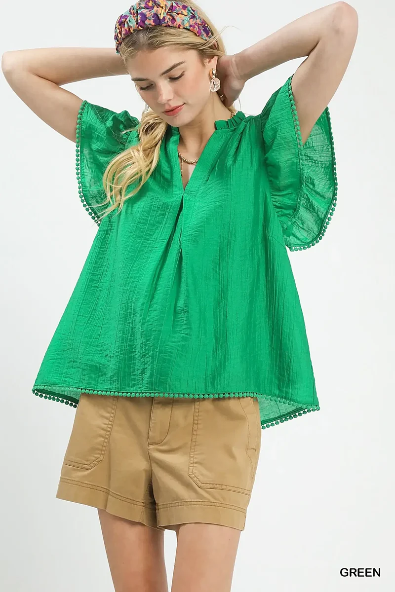 Smaragdgroene top met ruchesmouwen, pomponversiering en V-hals voor moeiteloze elegantie.