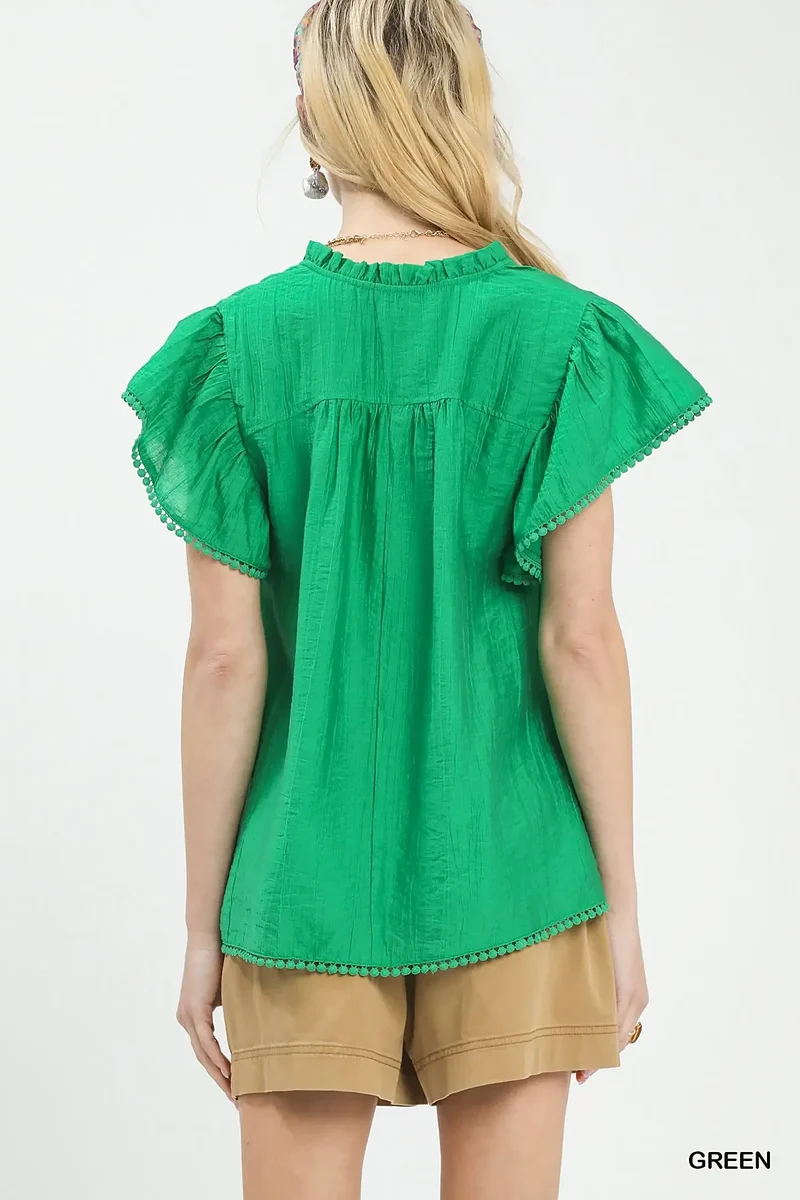 Smaragdgroene top met ruchesmouwen, pomponversiering en V-hals voor moeiteloze elegantie.