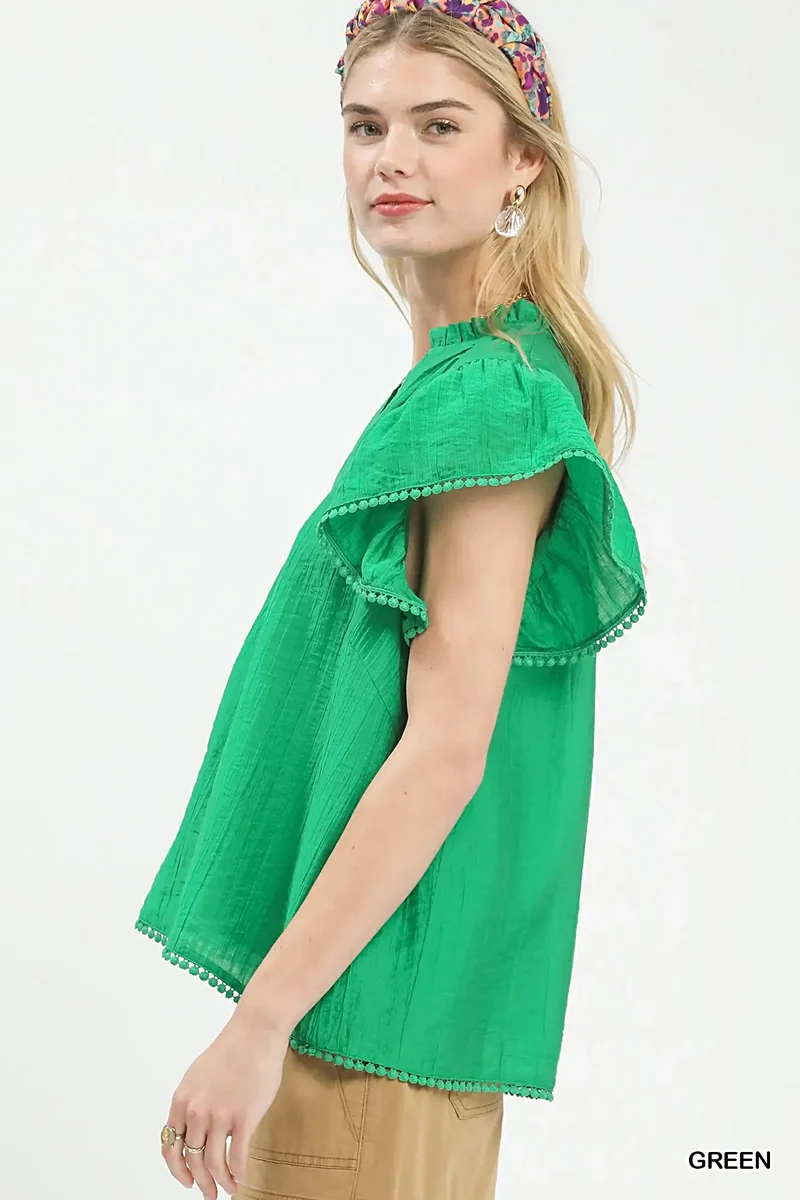 Smaragdgroene top met ruchesmouwen, pomponversiering en V-hals voor moeiteloze elegantie.