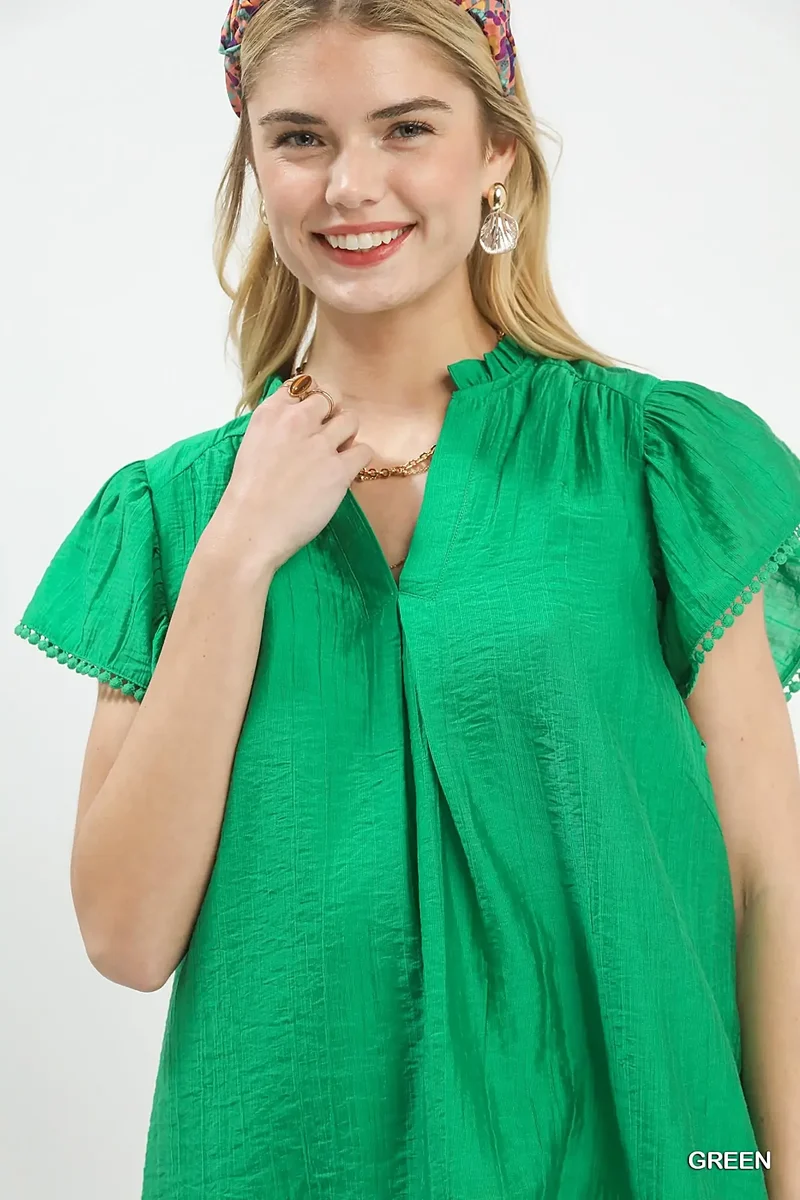 Smaragdgroene top met ruchesmouwen, pomponversiering en V-hals voor moeiteloze elegantie.