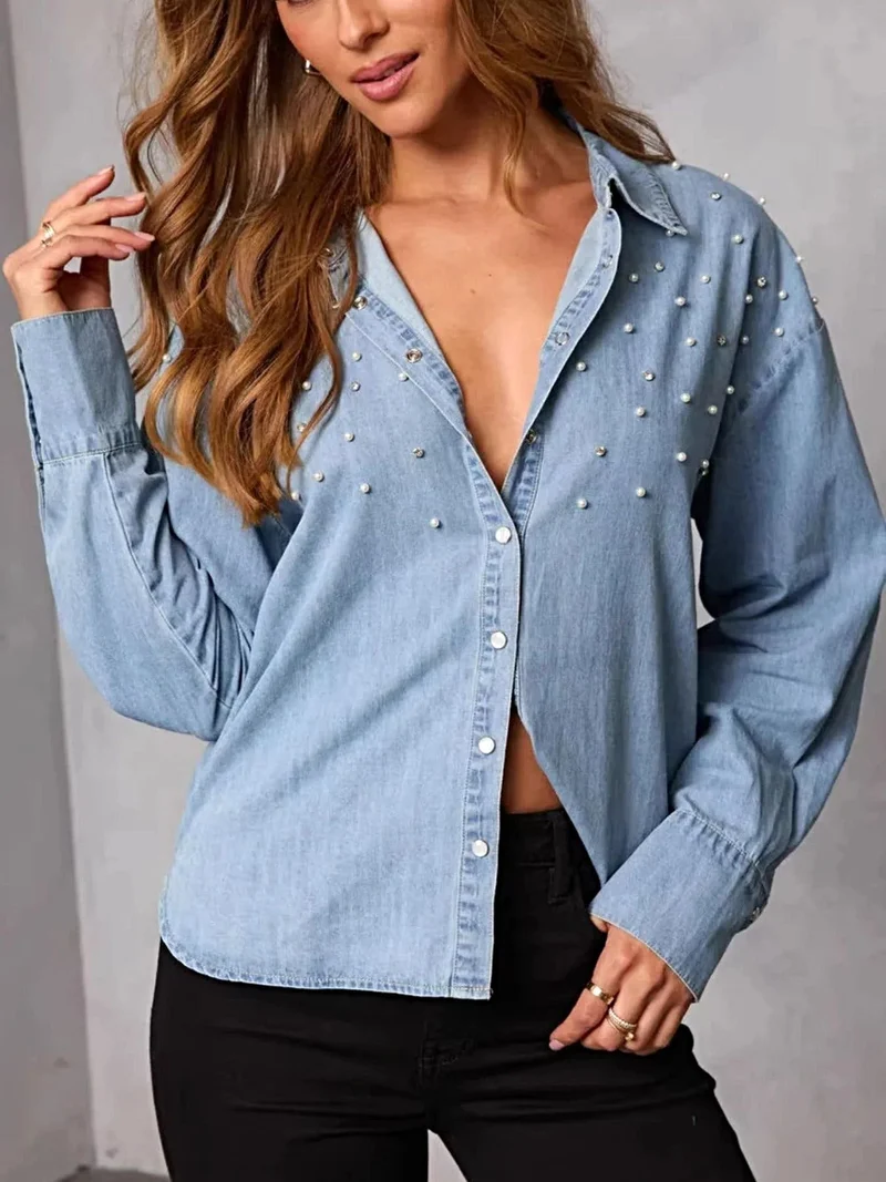 Elegant denim overhemd met parelversiering en knoopsluiting – een tijdloze modeklassieker.