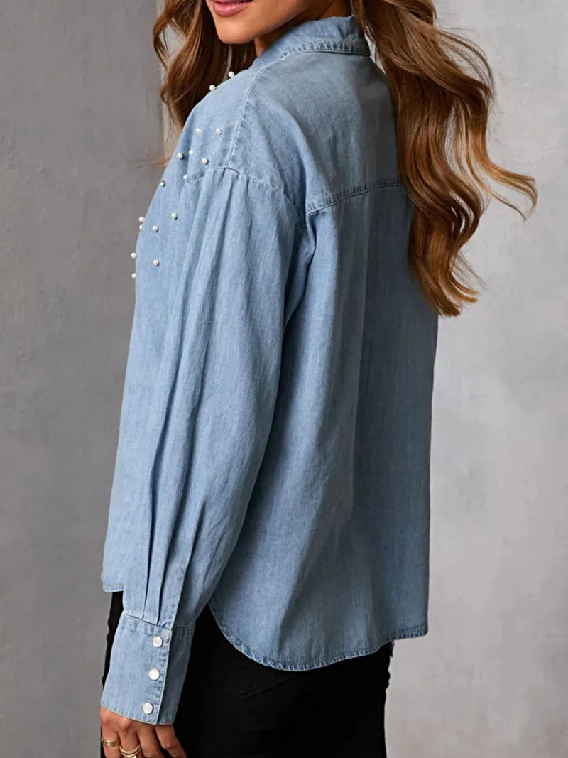 Elegant denim overhemd met parelversiering en knoopsluiting – een tijdloze modeklassieker.