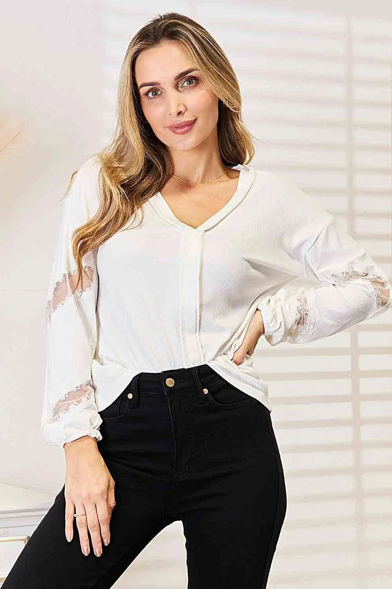 Verfijnde blouse met V-hals, verlaagde schouders en elegante kanten details.
