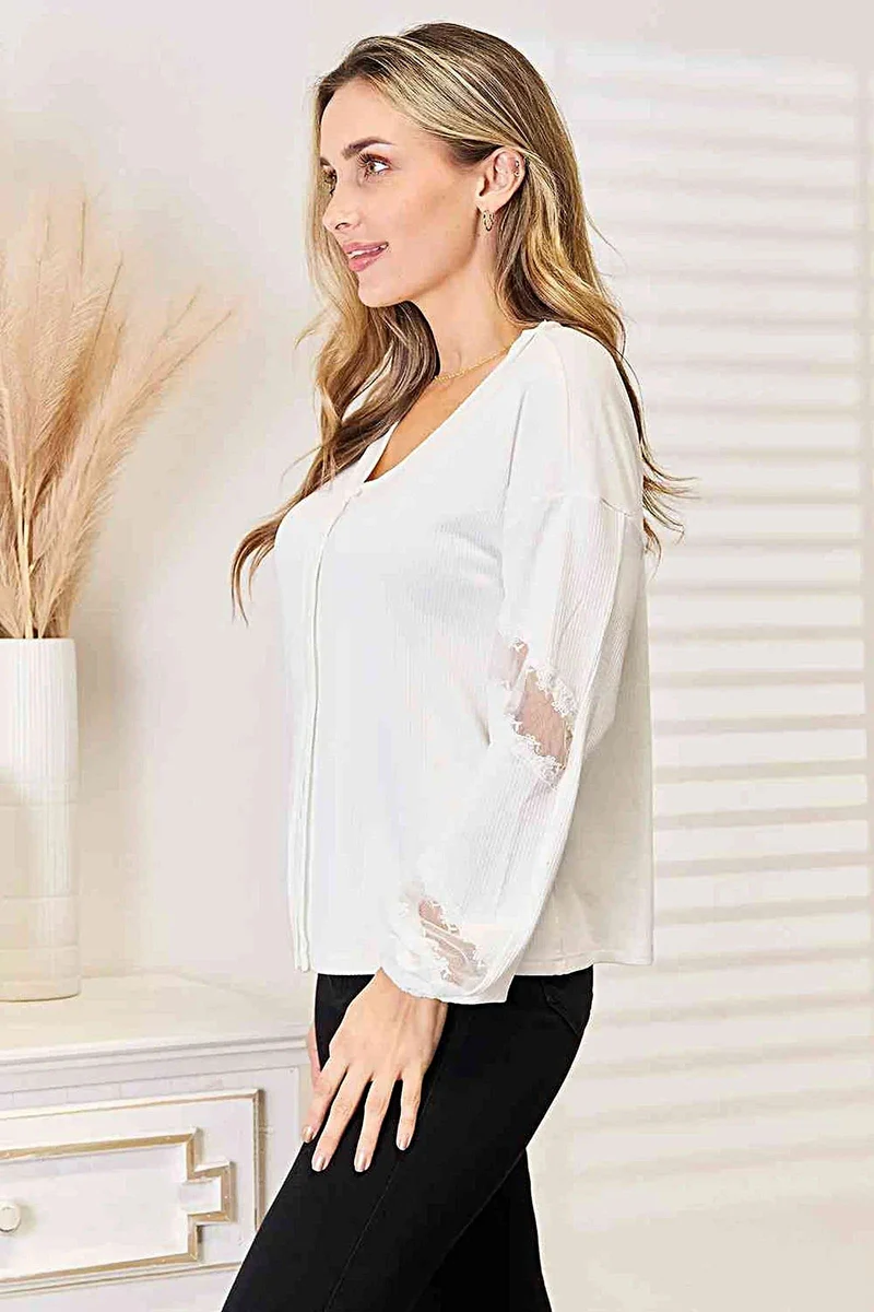 Verfijnde blouse met V-hals, verlaagde schouders en elegante kanten details.