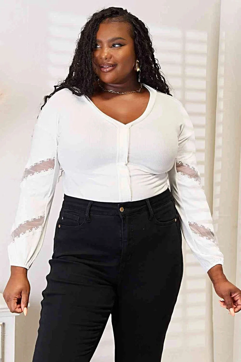 Verfijnde blouse met V-hals, verlaagde schouders en elegante kanten details.