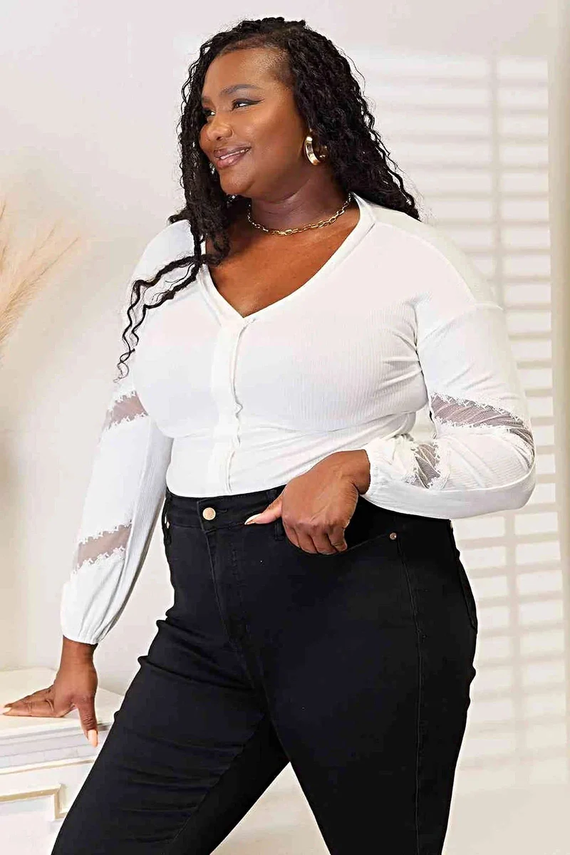 Verfijnde blouse met V-hals, verlaagde schouders en elegante kanten details.