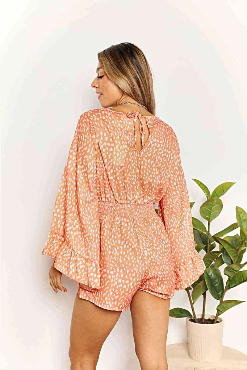 Chique jumpsuit met uitlopende mouwen, overslagkraag en smockdetails, levendige print.