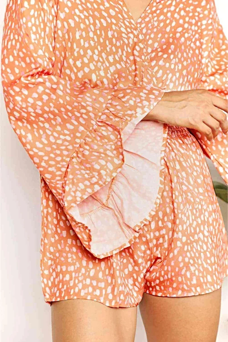 Chique jumpsuit met uitlopende mouwen, overslagkraag en smockdetails, levendige print.